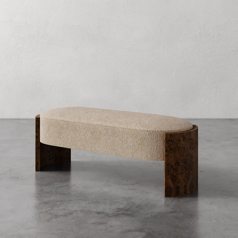 Lemieux et Cie Benoit Bench in natural bouclé with curved Maple burl legs, upholstered bench on polished concrete floor against plaster walls.