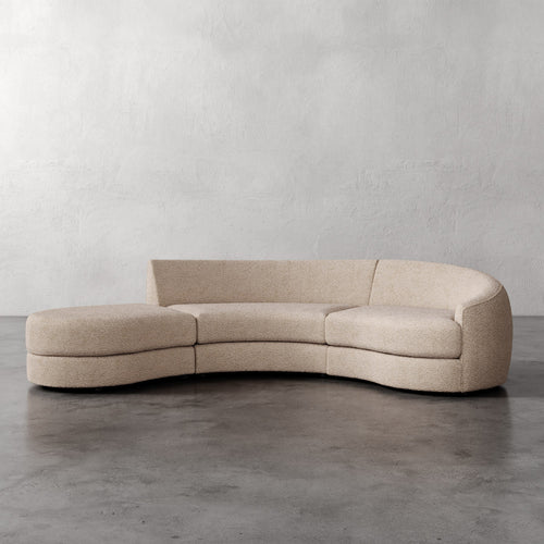 Lemieux Et Cie Rulmann 3-Piece Right Sectional Beige curved sofa on a gray floor with a plain gray wall background