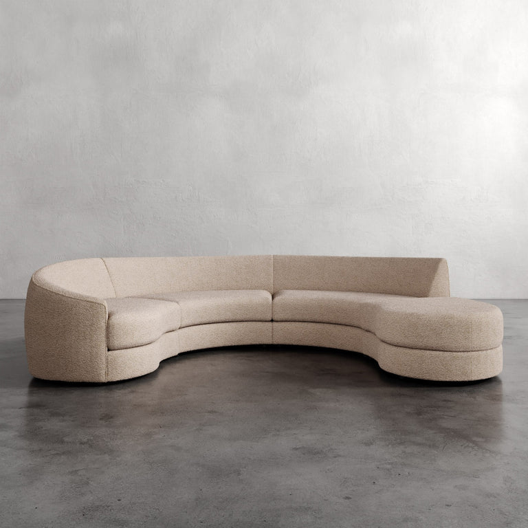 Lemieux Et Cie Rulmann 4-Piece Left Sectional Beige curved sofa on a gray floor with a plain wall background