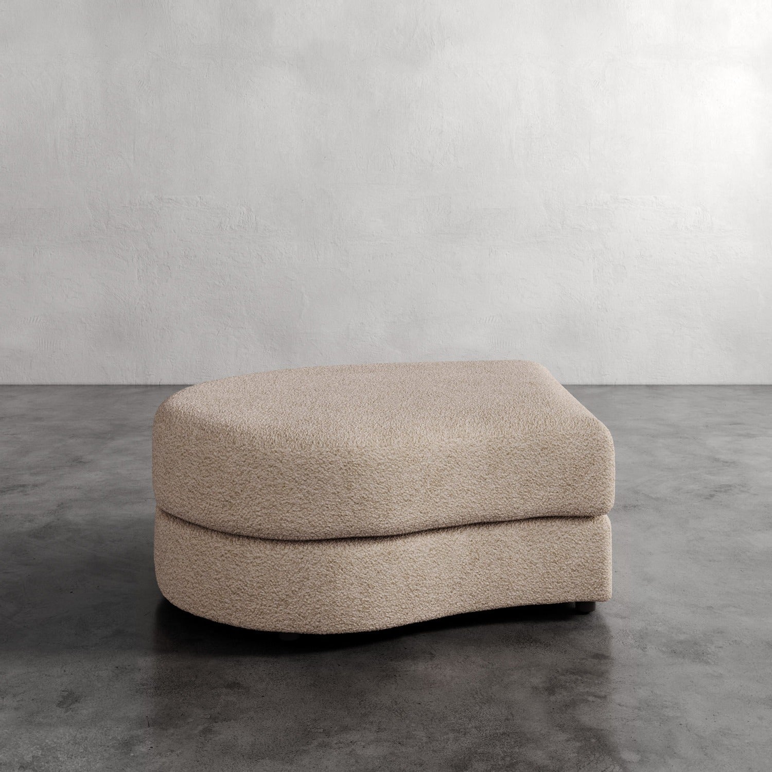 Lemieux Et Cie Rulmann Left Ottoman Beige ottoman on a gray concrete floor with a plain white wall background