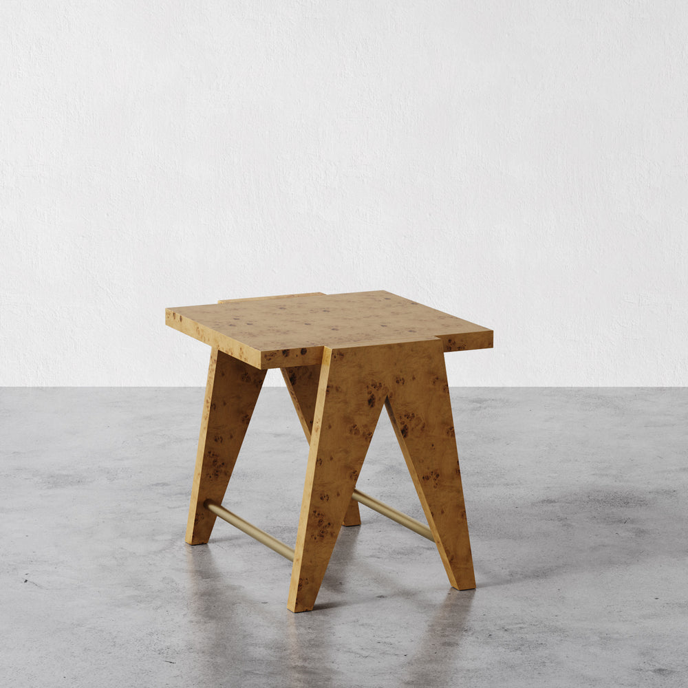 Lemieux et Cie Adrien side table in mappa burl with aged brass accents, angular geometric side table on concrete floors against white walls.