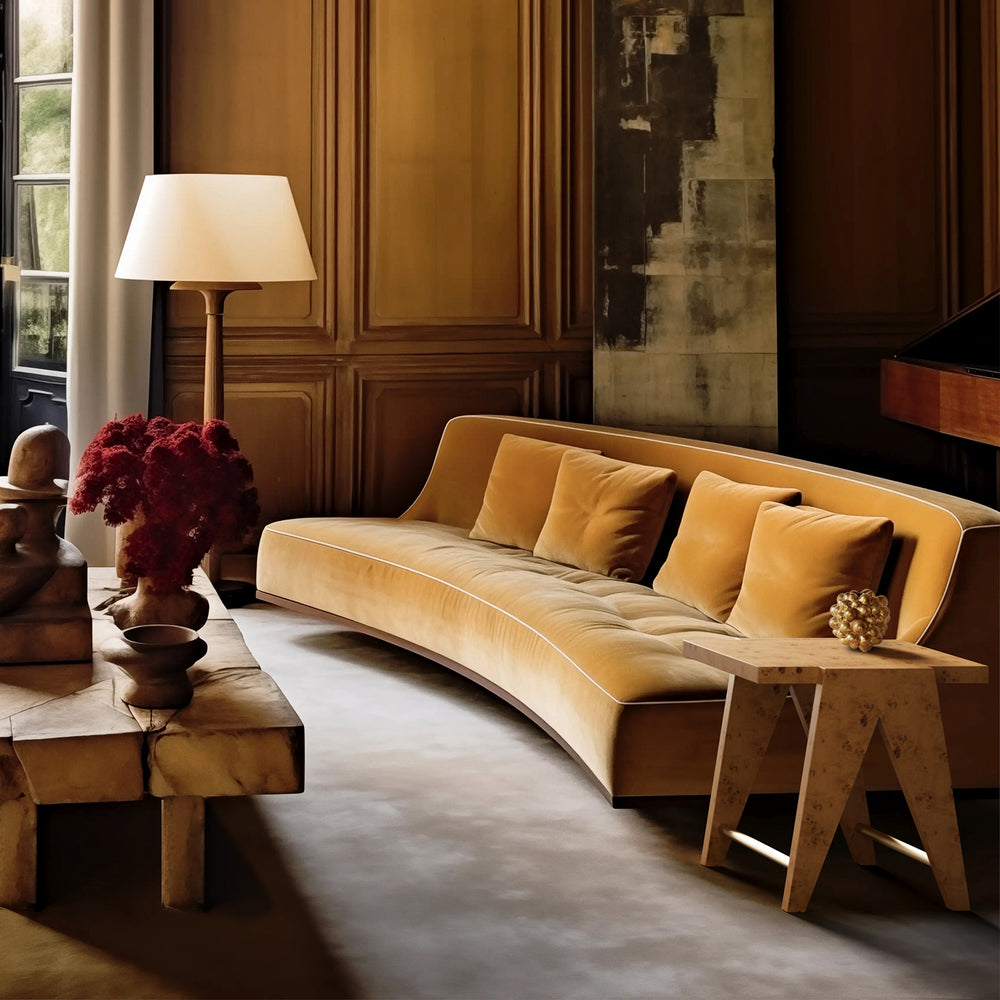 Lemieux et Cie Adrien Side Table in mappa burl with aged brass, modern A-frame silhouette shown beside a sofa in a wood-paneled room.