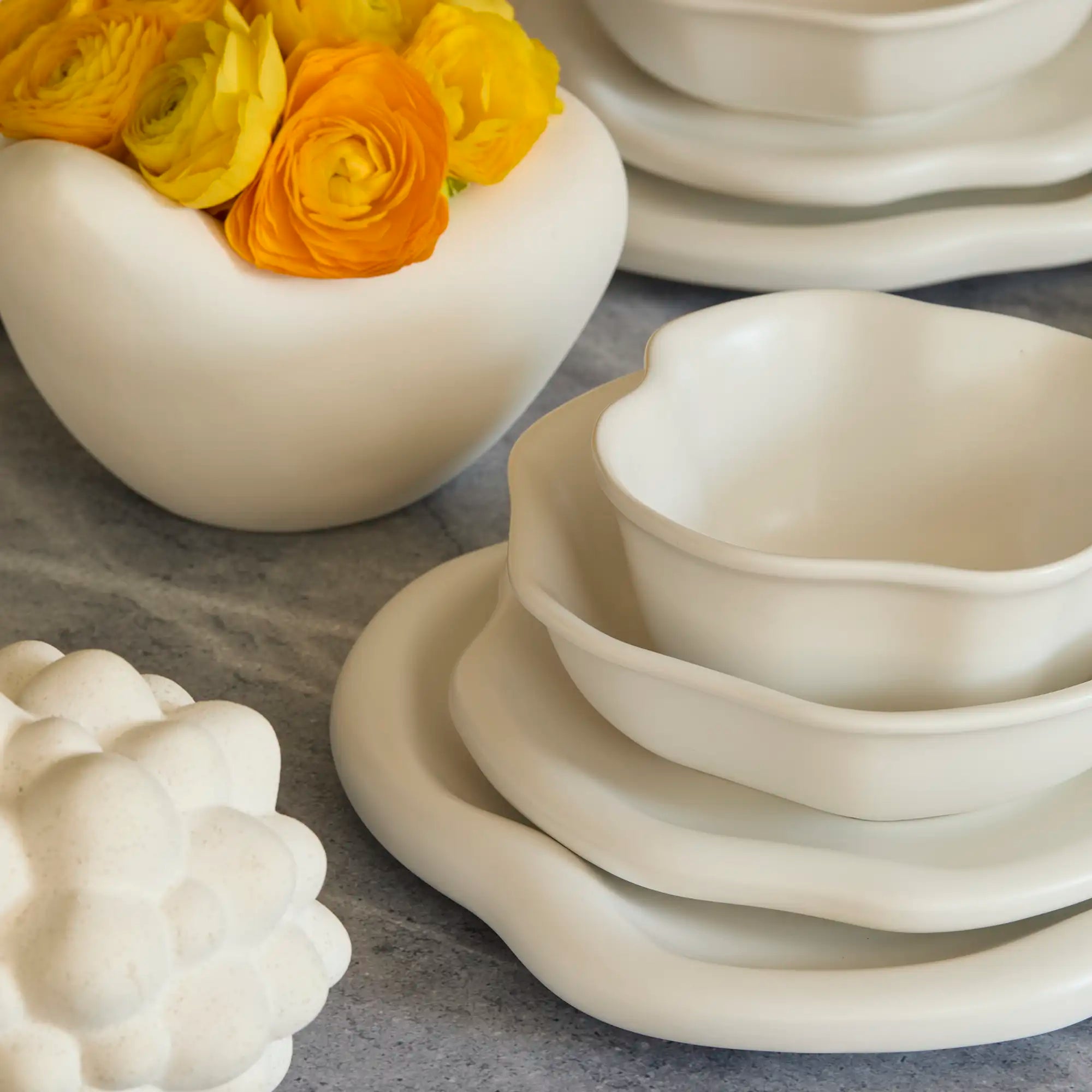 Lemieux et Cie Amorphous Dinnerware Set in soft white matte glaze, stoneware plates with organic asymmetrical edges, styled on stone surface with ceramic bowls.