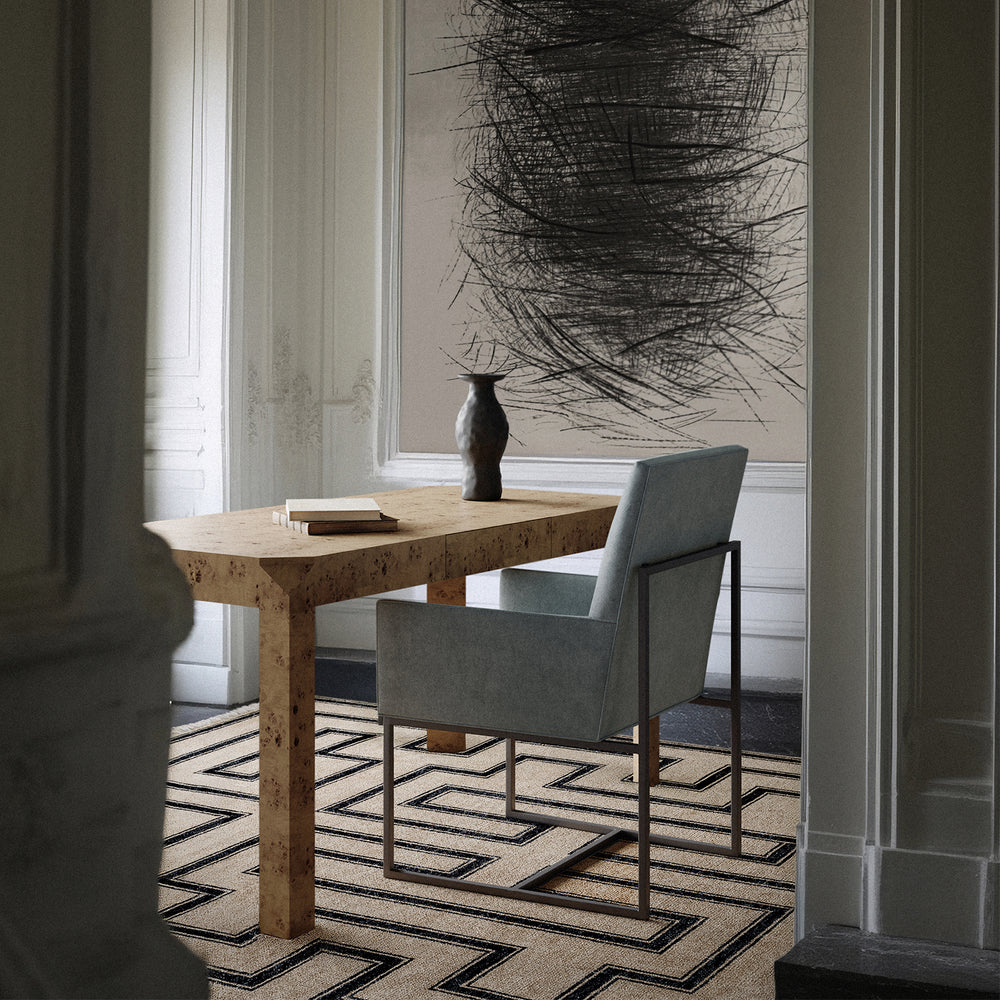 Lemieux et Cie Marquise Noire Handmade Wool Rug with geometric Art Deco pattern in cream and charcoal, styled in a dining room with stone table and chair.