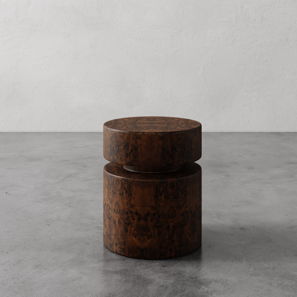 Lemieux et Cie Avenir Side Table, sculptural cylindrical table with stacked form in warm aged finish, shown on concrete floor against neutral plaster wall.