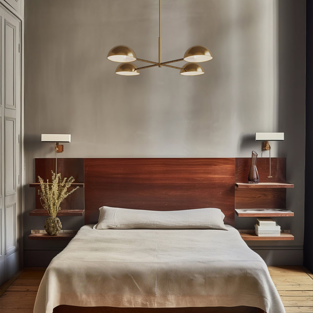 Lemieux et Cie Balleroy chandelier in brass with rattan-wrapped arms and dome shades, suspended above a bed with warm wood headboard in a neutral bedroom with wood floors.