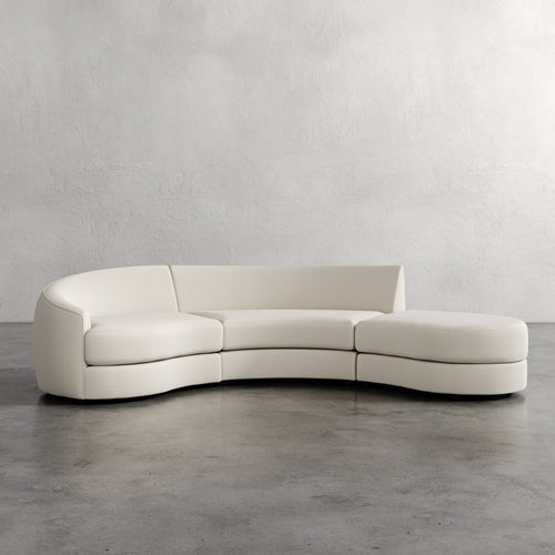 Modern white curved sofa against a plain wall. Rulmann 3-Piece Left Sectional Basket Natural
