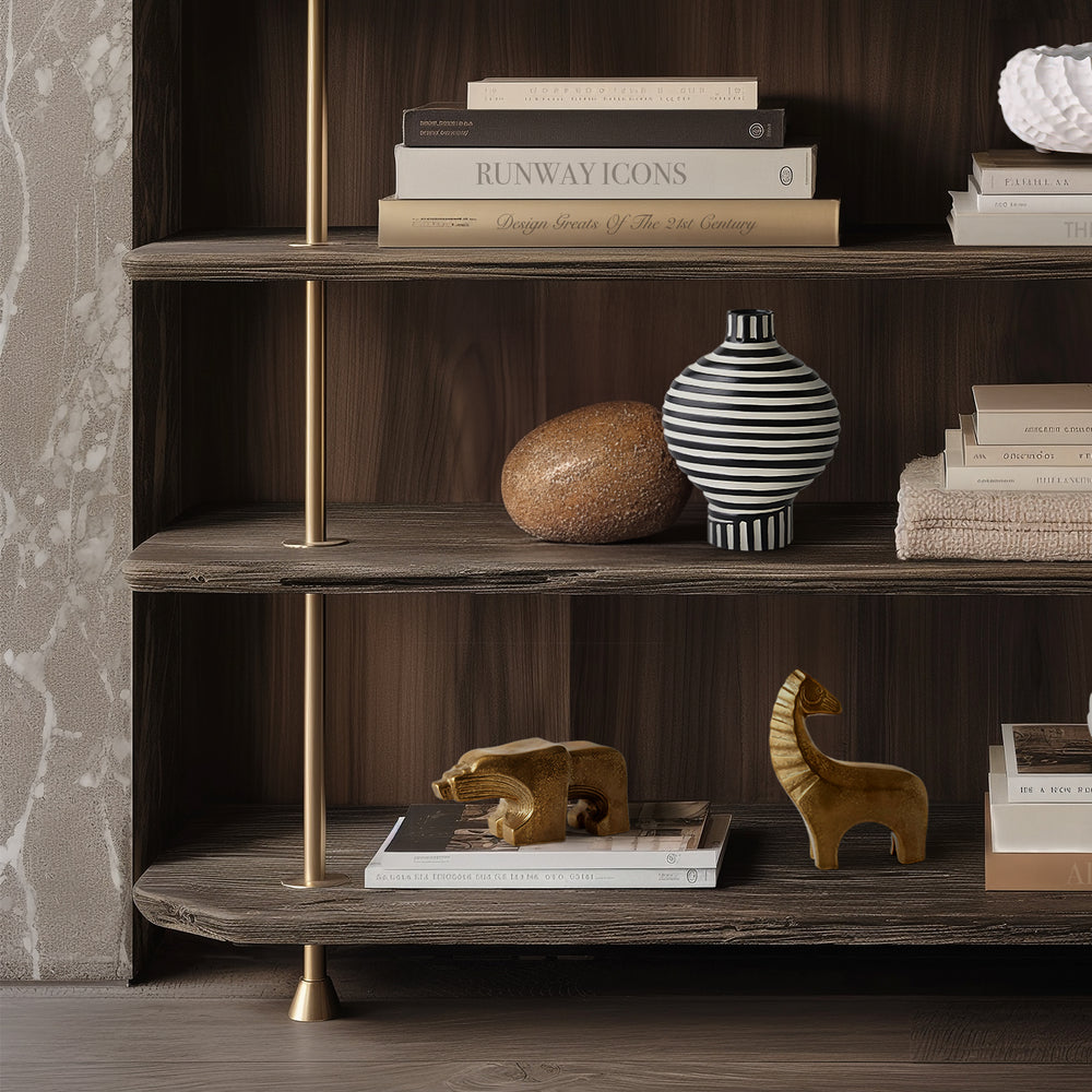 Lemieux et Cie animal objects including striped ceramic vase, textured orb, and sculptural figures on dark wood shelving with brass frame in a sitting room.