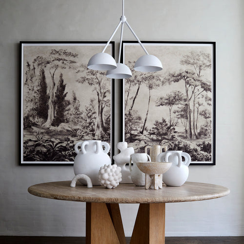 Lemieux et Cie Bois de Boulogne diptych print, framed panoramic woodland scenes hung above a round stone-top dining table with sculptural ceramic vessels.