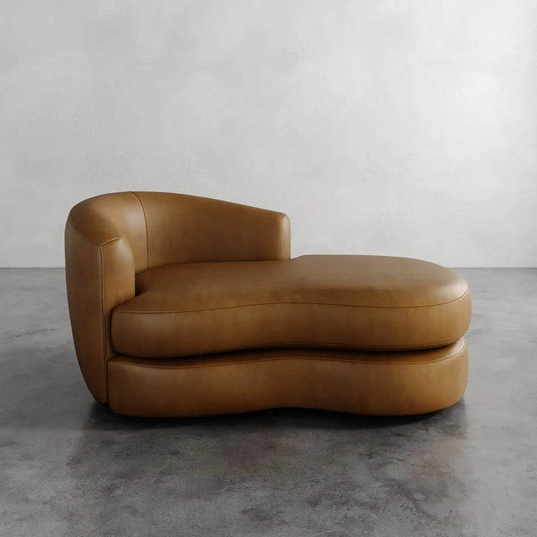 Lemieux et Cie Rulmann Leather Left Arm Chaise in warm caramel leather, sculptural low-slung chaise on polished concrete floor against neutral walls.