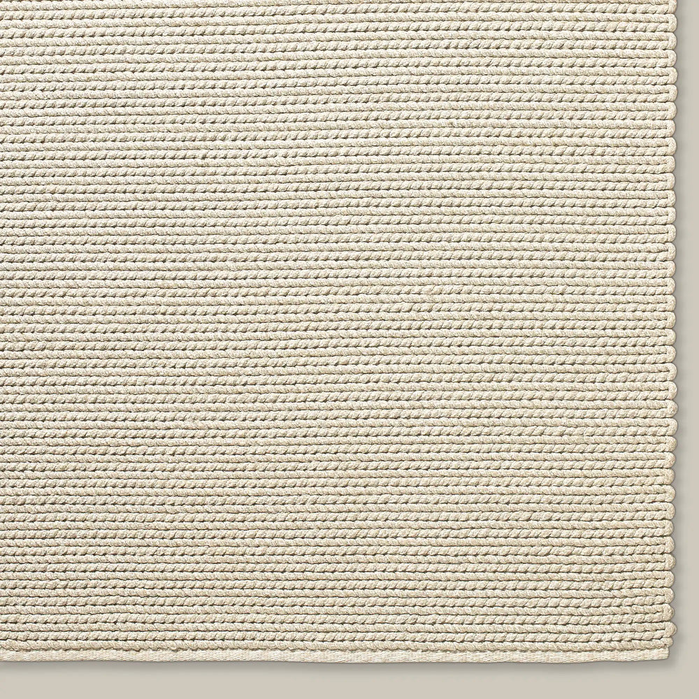Lemieux et Cie Tricot Handwoven Outdoor Rug in cream, textured woven rug shown in close detail on neutral studio backdrop.