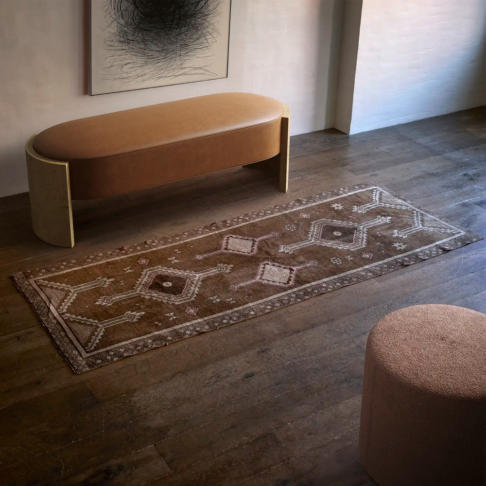 Lemieux et Cie Vintage 1960's Anatolian Rug with geometric diamond motifs in warm brown and ivory tones, shown on aged wood floors with curved bench.