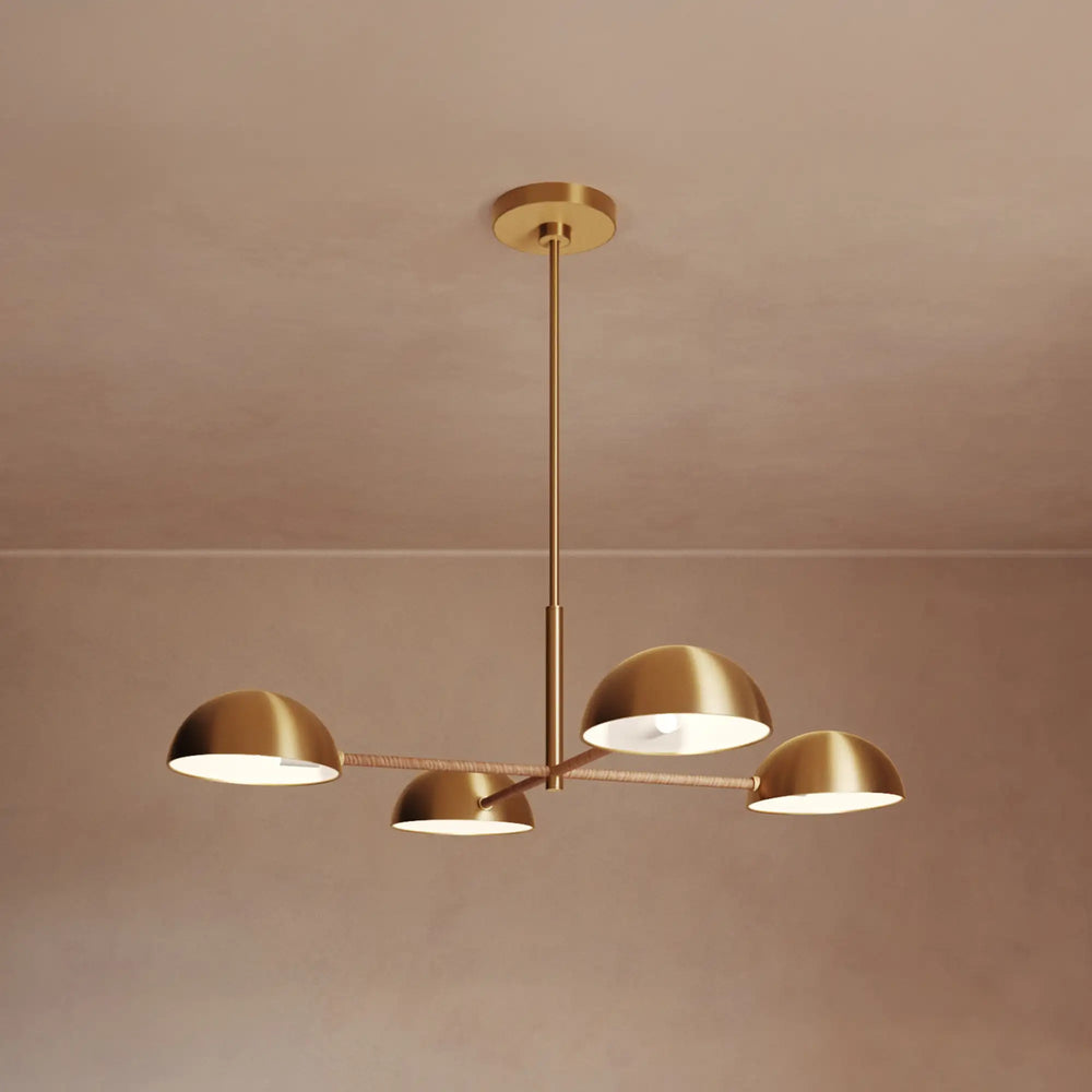 Lemieux et Cie Balleroy Chandelier in brass with rattan-wrapped arms, four-arm pendant with dome shades, shown against warm neutral walls.