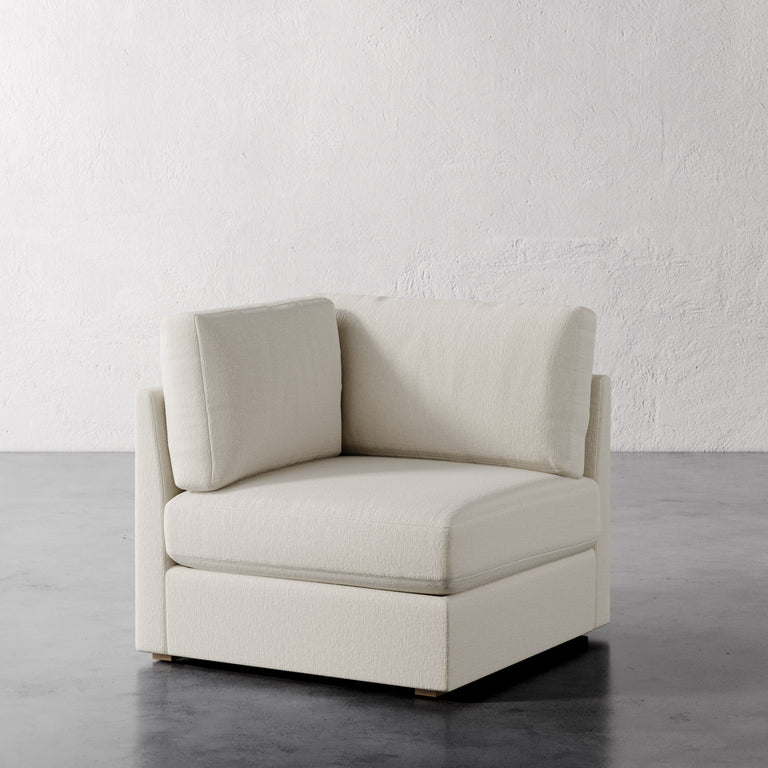 Lemieux Et Cie Chanaux Corner Chair Beige armchair on a gray floor with a white textured wall background