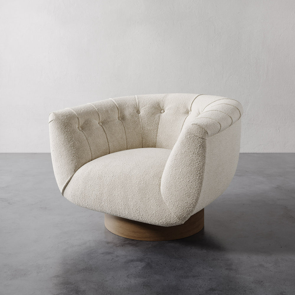 Cream velvet Lemieux et Cie Lune Swivel Chair with rounded tufted back and sculptural silhouette, set against a white wall and gray floor.