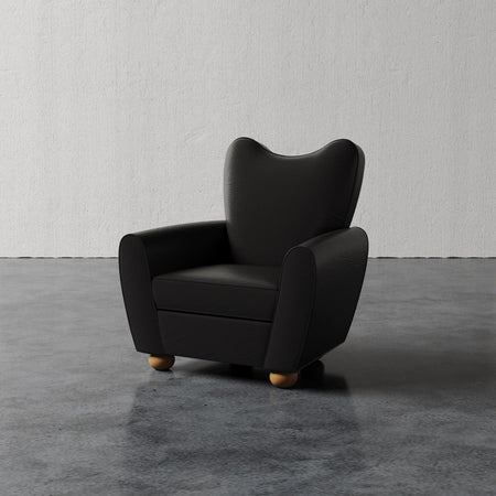 Lemieux et Cie Danielle Chair in dark charcoal, sculptural wingback form on rounded feet, shown on polished concrete floor against neutral plaster wall.