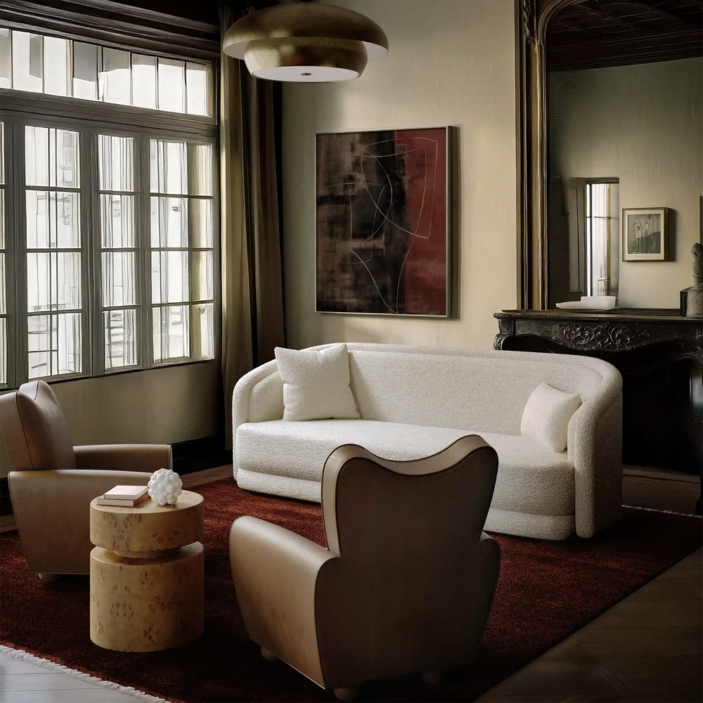 Lemieux et Cie Danielle Chair in warm neutral leather, sculptural curved form on dark floor in a sitting room with abstract art and tall windows.