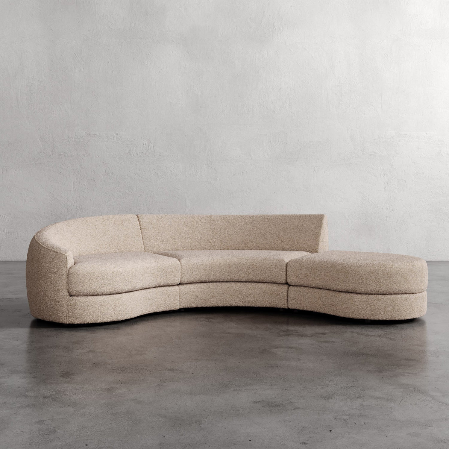 Beige curved sofa on a gray floor with a plain white wall background. Rulmann 3-Piece Left Sectional Eru Boucle