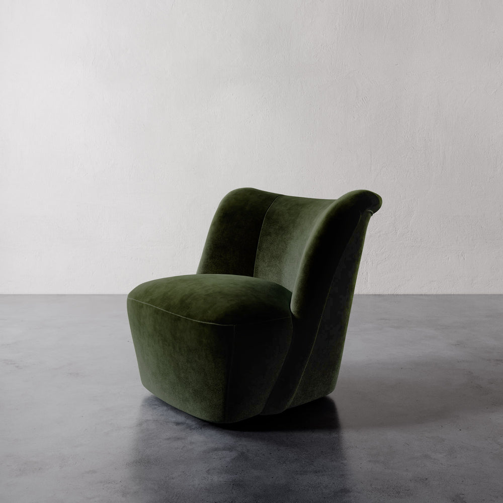 Lemieux et Cie Aurélie Swivel Chair in deep green, sculptural lounge chair with rounded organic form, on polished concrete floor against white plaster wall.
