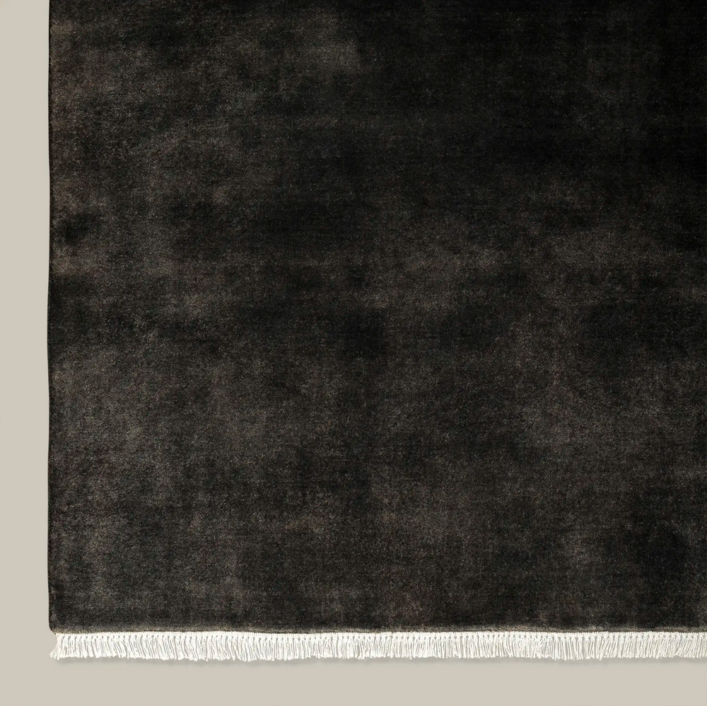 Lemieux et Cie Plume Handmade Wool Rug in charcoal, close-up detail of hand-loomed texture with fringe edge, shown on neutral studio backdrop.