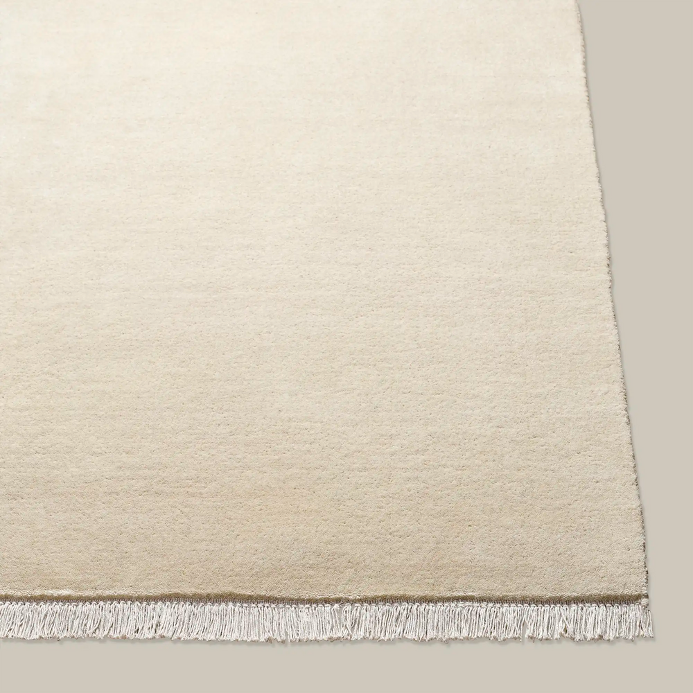 Lemieux et Cie Plume Handmade Wool Rug in Natural, close-up detail showing plush texture and fringe edge, shown on white backdrop.