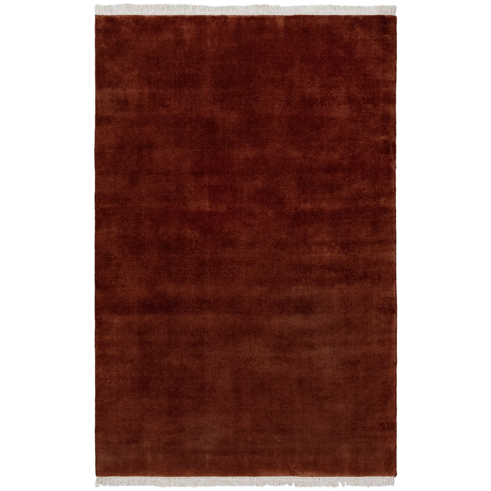 Lemieux et Cie Plume Handmade Wool Rug in Merlot, deep rust-toned rug with fringe detail, shown on white studio backdrop.