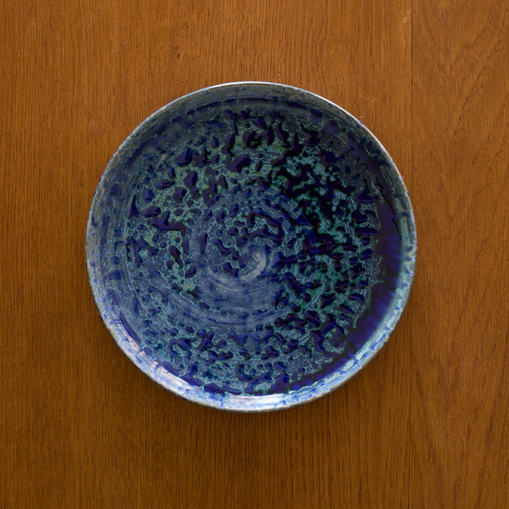 Lemieux et Cie Hanami Stoneware Salad Plate in indigo with organic textured glaze, ceramic tableware shown on warm wood surface.