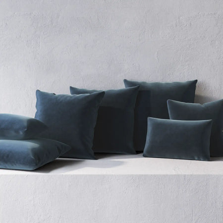 Lemieux et Cie Throw Pillows in deep teal, square and lumbar pillows arranged against textured white plaster wall in soft daylight.