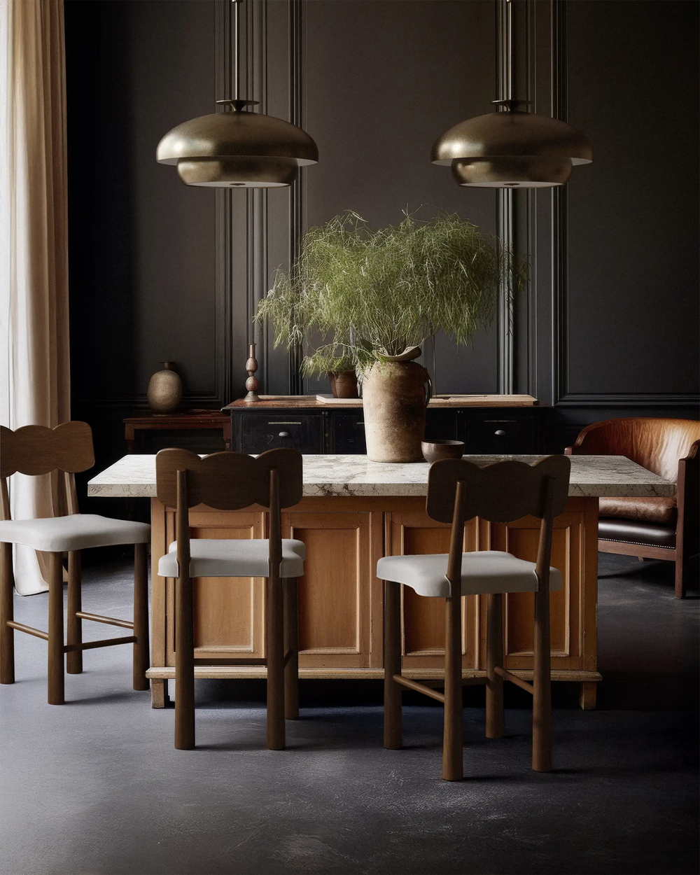Lemieux et Cie Madeleine Counter Stool in walnut with upholstered seat, gathered around marble-topped dining table in dark-paneled room with stone floor.