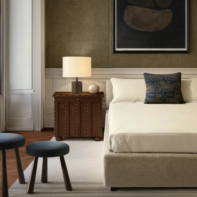 Lemieux et Cie Tiger Velvet Pillow in deep indigo performance velvet, decorative pillow with Tibetan tiger motif, styled on upholstered bed in bedroom with wood floors and textured neutral walls.