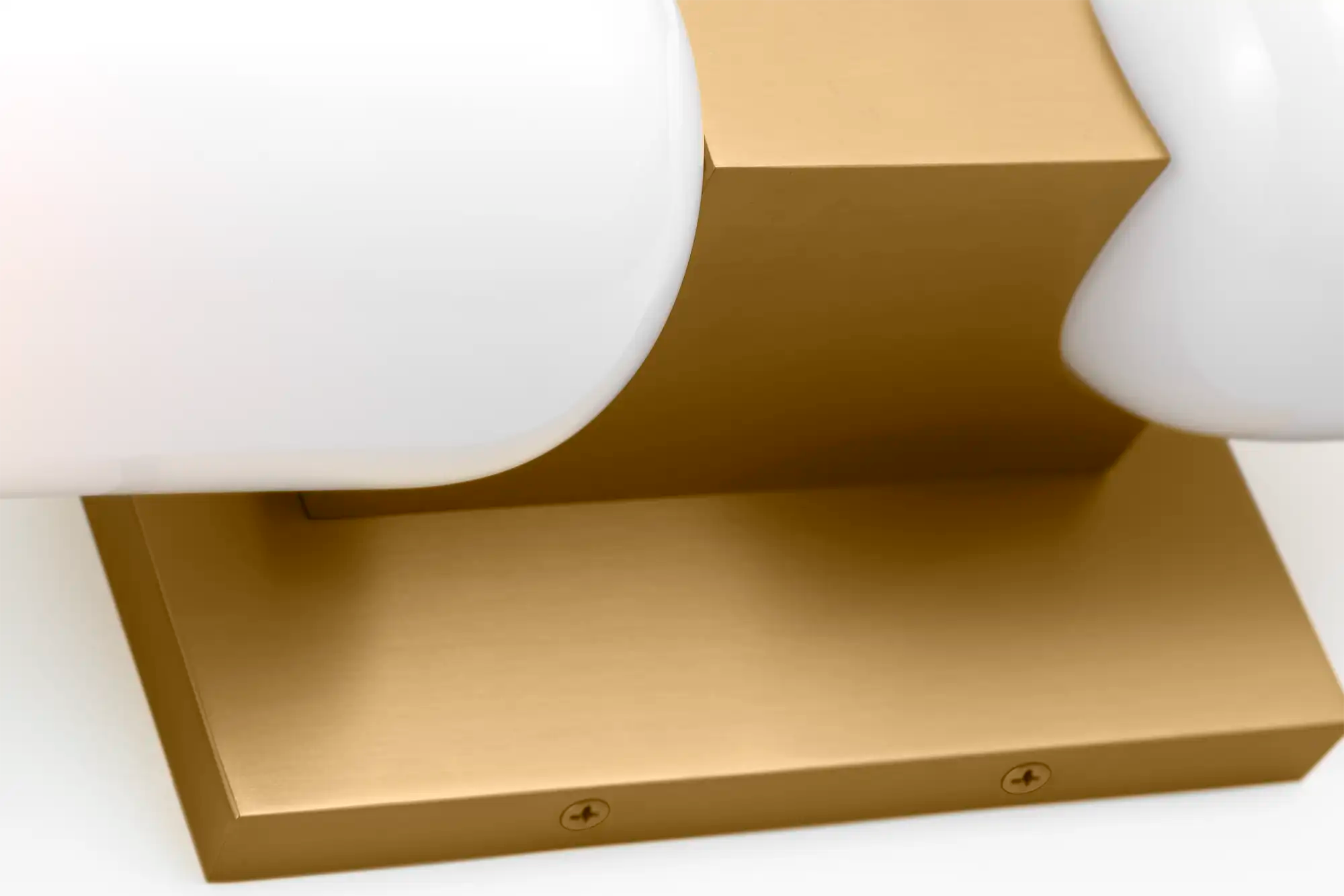 Lemieux et Cie Maroux Double Sconce in burnished brass with opal glass shade, detail of stepped wall mount on white backdrop.