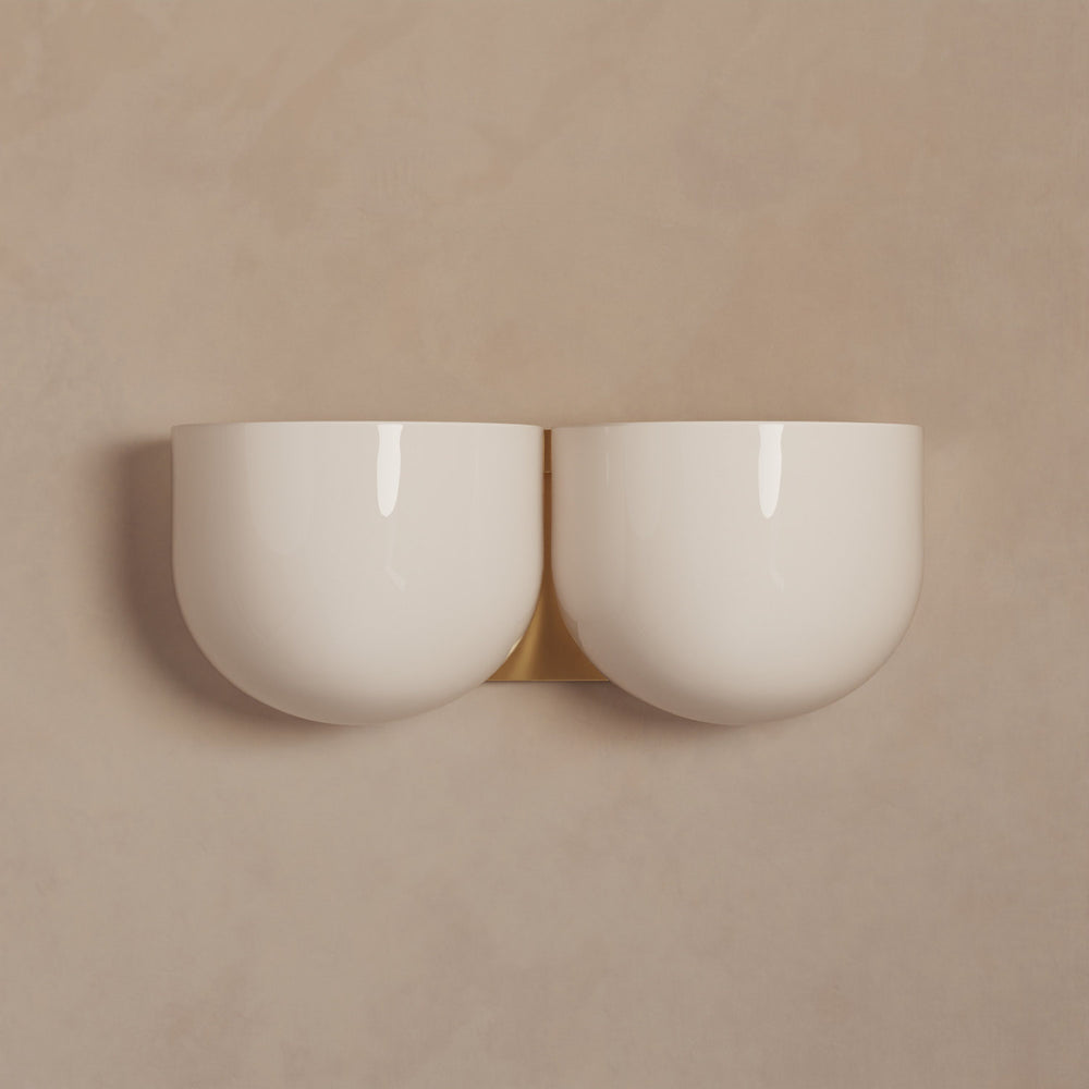 Lemieux et Cie Cheverny Sconce, double bowl-form wall light in ivory with warm brass backplate, mounted on neutral plaster wall.