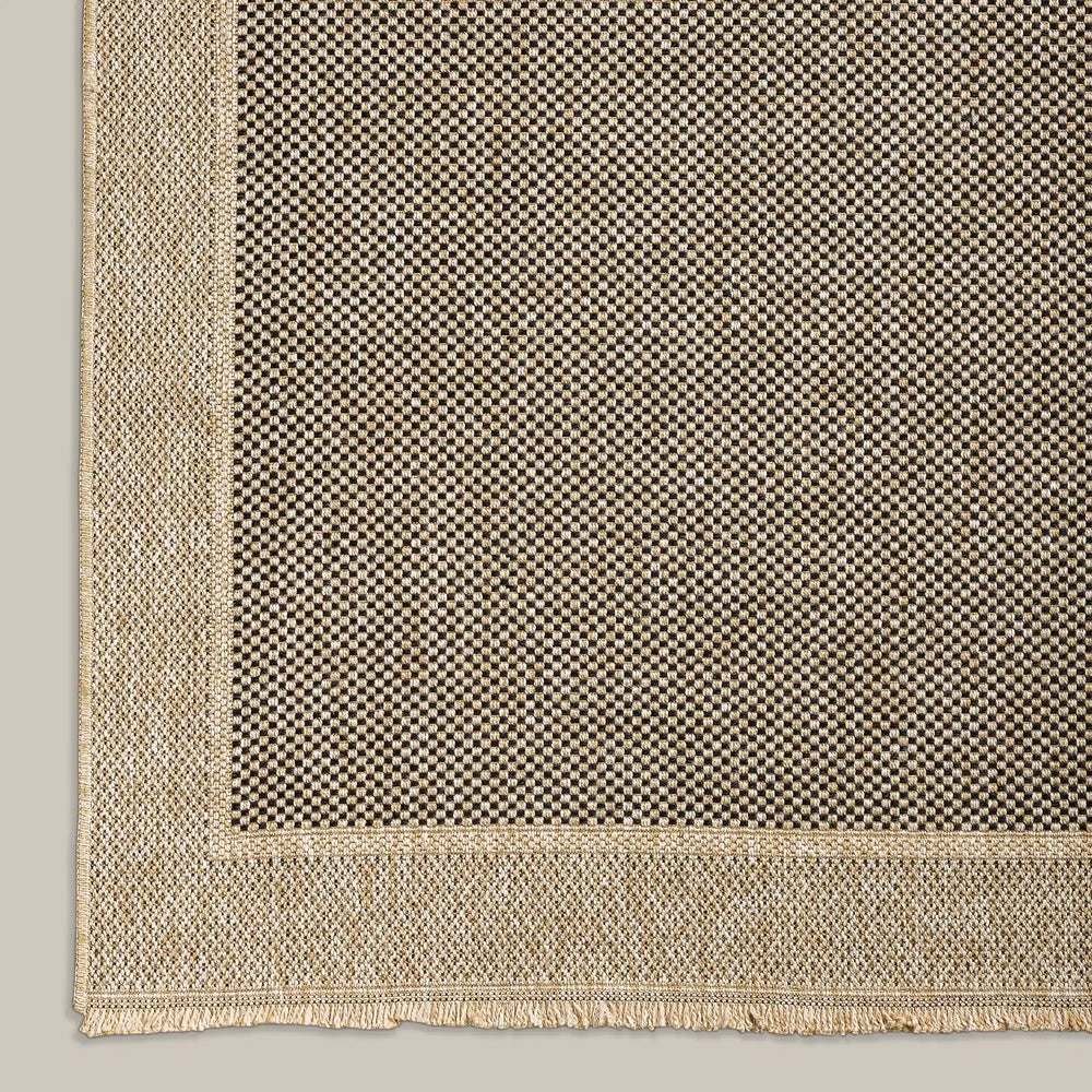Lemieux et Cie Panier Outdoor Rug in ivory and charcoal checkerboard pattern with bordered edge, flatweave rug shown on neutral studio backdrop.