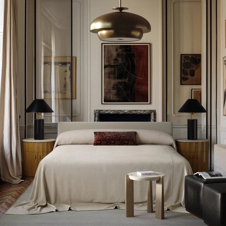 Lemieux et Cie Gérard Bed, low-profile platform bed with wrapped headboard, styled in bedroom with white paneled walls and parquet flooring.