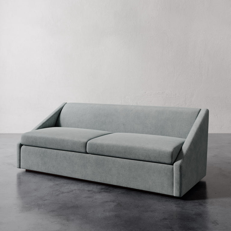 Lemieux et Cie Fontaine Sofa in pale gray upholstery, architectural sofa with structured silhouette, shown on polished concrete floor against textured white walls.