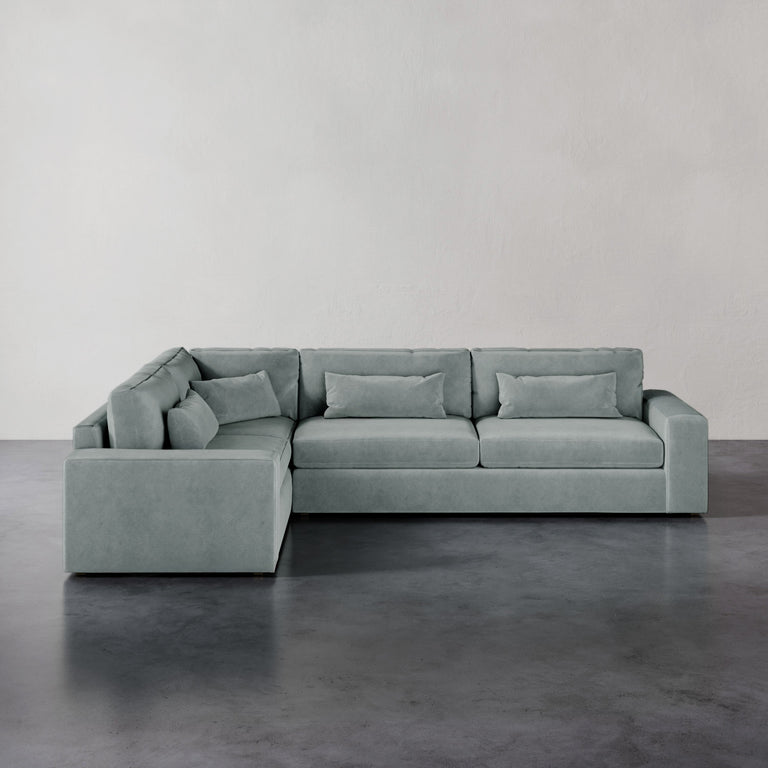 Lemieux et Cie Lacroix Right Arm Sectional in sage grey, modular sofa with bolster pillows, shown on dark concrete flooring against neutral walls.