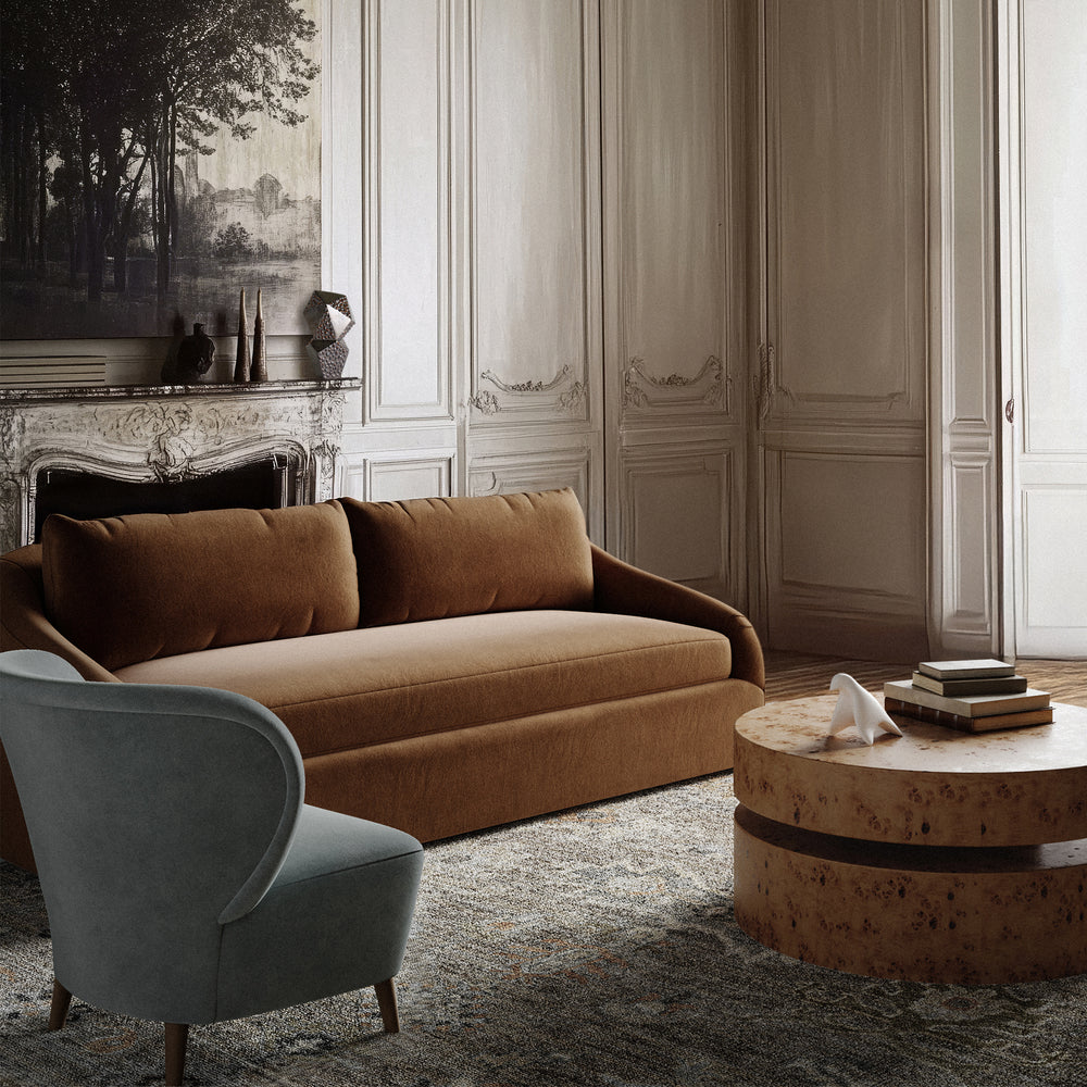 Lemieux et Cie Rousseau Sofa in warm tan upholstery, low-profile sofa with tufted back cushions, styled in Parisian sitting room with carved paneled walls and carved stone mantel.