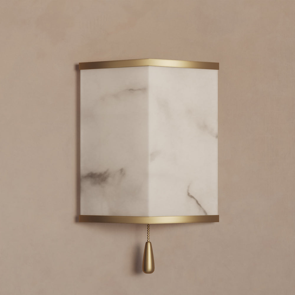 Lemieux et Cie Cleor Small LED Sconce, wall-mounted fixture with cylindrical marble shade and brass frame, shown on warm neutral plaster wall.