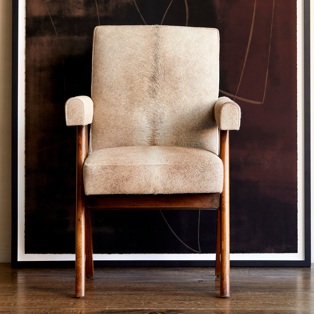 Lemieux et Cie Chaumont chair in natural hide with warm wood frame, armchair on dark wood flooring against burgundy and black abstract artwork.