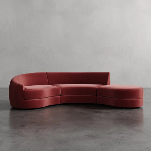Lemieux et Cie Rulmann 3-Piece Left Sectional in terracotta upholstery, curved modular sofa on polished concrete floor against textured plaster wall.