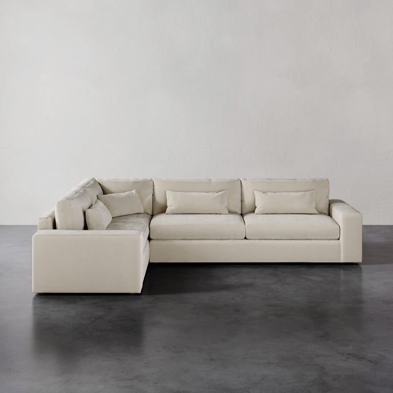 Lemieux et Cie Lacroix Right Arm Sectional in ivory, low-profile modular sofa with bolster pillows, shown on dark concrete floor against neutral walls.