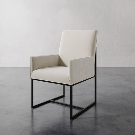 Lemieux et Cie Dupont Dining Arm Chair in ivory with geometric dark frame, shown on polished concrete floor against textured white walls.
