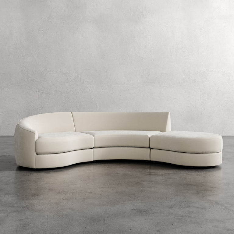 Modern curved white sofa against a plain wall. Rulmann 3-Piece Left Sectional Strie Bisque