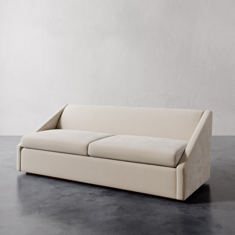Lemieux et Cie Fontaine Sofa in ivory upholstery, architectural low-profile form with structured silhouette, shown on polished concrete floor against textured white walls.