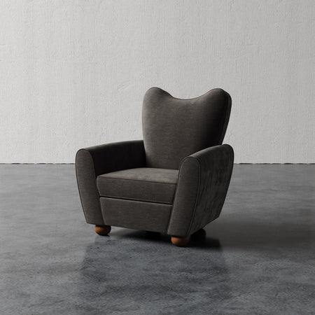 Lemieux et Cie Danielle Chair with sculptural wingback silhouette and rounded arms, shown on polished concrete floor against textured plaster wall.