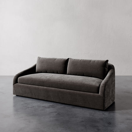 Lemieux et Cie Rousseau Sofa, low-profile sofa with rounded arms and single bench seat cushion, shown on polished concrete flooring.
