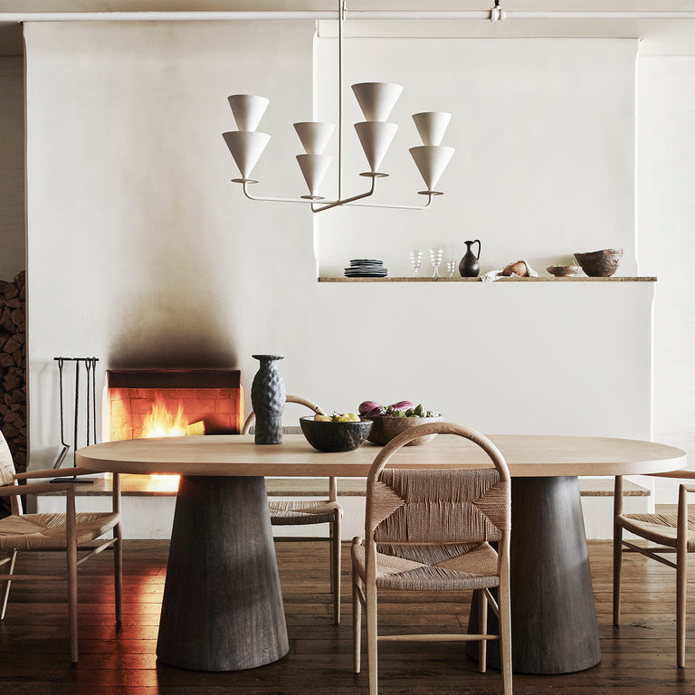 Lemieux et Cie Cornet 4 Light Large Chandelier, a luxury lighting fixture in white cast plaster above a dining table with Pernelle Dining Chairs and a lit fireplace.