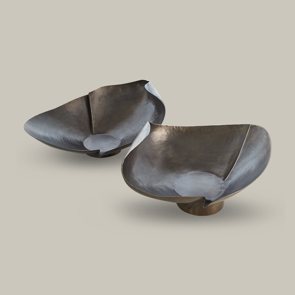 Lemieux et Cie sculptural decorative bowls in dark patinated finish, organic curved forms on pedestal bases shown on neutral studio backdrop.