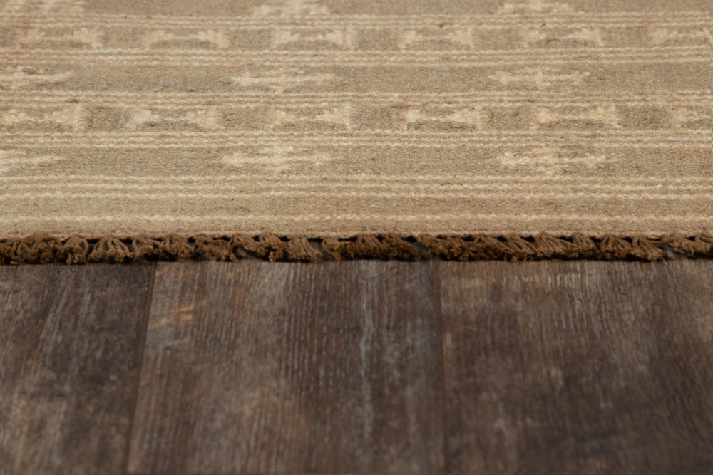 Lemieux et Cie Metlili rug in wool, handwoven carpet with aged finish, detail view of low-profile edge shown on weathered wood flooring.
