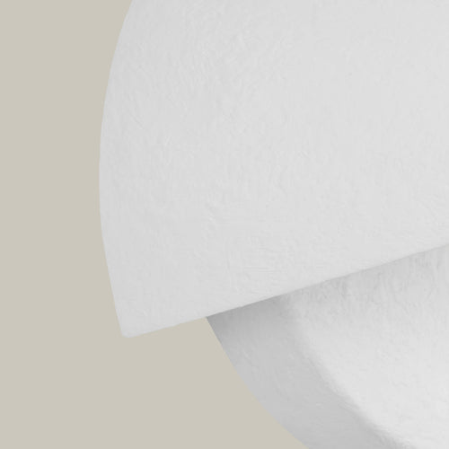 Lemieux et Cie Beaunay Small Sconce in steel and cast plaster, a luxury lighting fixture showing the cast plaster texture and half of the bowl-shaped shade from a tilted close-up view on an off-white background.